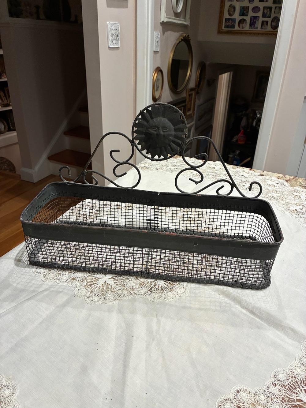 Black metal wire basket with decorative scrollwork and sunburst design